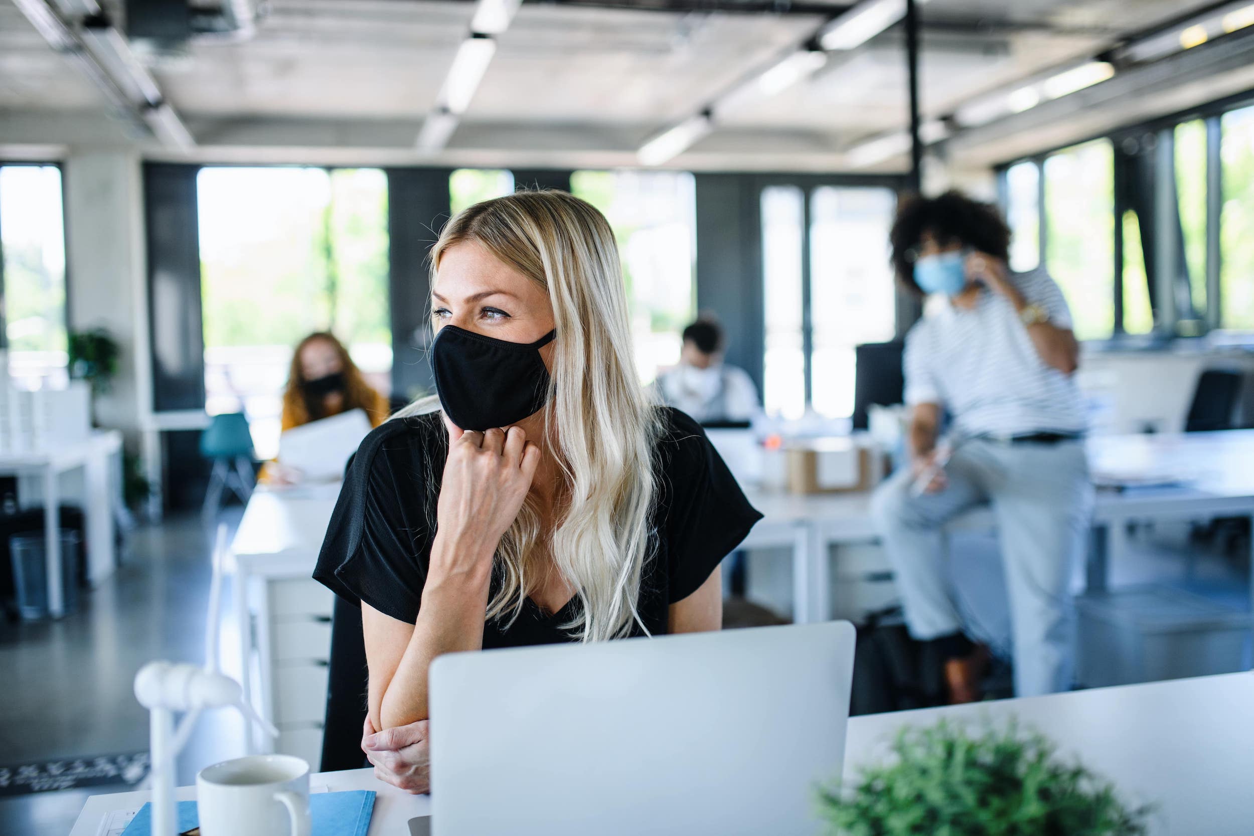 young woman in face mask back at work in an office